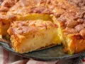 Ein saftiger apfelkuchen mit schale, goldbraun gebacken und mit Zimt bestreut. Ein Stück wird gerade herausgehoben.