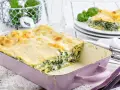 Herzhaftes Spinat-Lasagne-Rezept in einer lila Auflaufform, mit frischem Basilikum garniert.