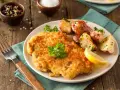 Goldbraunes Schnitzel, perfekt paniert, mit Rosmarinkartoffeln und Zitrone auf einem Teller. Ein Genuss, der zeigt, wie man ein Schnitzel paniert.