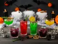 Gruselige Halloween Cocktails mit Alkohol: grüne, rote und gelbe Drinks, garniert mit Beeren und Zitronen. Nebel und Spinnen sorgen für Gruselstimmung.