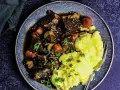 Herzhaftes Boeuf Bourguignon mit zartem Rindfleisch, Karotten und Pilzen, serviert mit cremigem Kartoffelpüree und Petersilie.