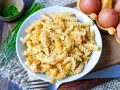Fusilli-Nudeln mit Rührei, gewürzt mit Pfeffer. Daneben liegen frische Eier und Schnittlauch. Ein einfaches, aber leckeres Gericht: Nudeln mit Ei.