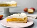 Ein Stück Apfel Schmand Torte auf einem rosa Teller, mit einer Schicht Apfelmus und Sahnehaube, garniert mit Zimt.