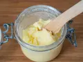 Frisch gemachte Butter in einem Glas, mit einem Holzspatel zum Butter selber machen.