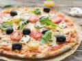 Leckerer Pizzaboden mit Joghurt, belegt mit Tomaten, Oliven und Pilzen.