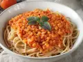 Herzhafte rote Linsen Bolognese auf Spaghetti, garniert mit frischen Kräutern. Ein köstliches und gesundes Gericht.