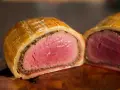 Ein perfekt zubereitetes Beef Wellington, saftig rosa im Inneren, umhüllt von goldbraunem Blätterteig.