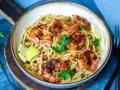 Ein Teller mit köstlichen Spaghetti mit Garnelen, garniert mit frischer Petersilie und Zitronenspalten.