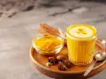 Ein Glas goldene Milch mit Kurkumapulver, Zimtstangen und Sternanis. Perfekt für ein wärmendes goldene milch rezept.