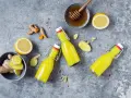 Zutaten für ingwer shot selber machen: frischer Ingwer, Zitrone, Honig und rote Pfefferflocken auf grauem Untergrund.