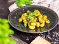 Gnocchi mit Spargel, garniert mit frischem Basilikum und Parmesan. Ein köstliches Gericht, das den Frühling auf den Teller bringt.