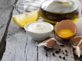 Cremige Mayonnaise mit gekochtem Eigelb und Joghurt, garniert mit Pfeffer, neben Zitrone, Knoblauch und Olivenöl.