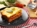 Ein Stück Lasagne mit Käse überbacken, garniert mit Basilikum. Perfekt für ein köstliches Lasagne Rezept.