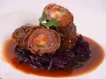 Zwei Rouladen mit Gemüsefüllung, serviert mit Rotkohl und Bratensoße. Köstliche Rouladen im Backofen zubereitet.