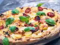 Eine köstliche Pizza Bianca mit Kartoffelscheiben, getrockneten Tomaten und frischem Basilikum.