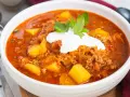 Herzhafte Mitternachtssuppe mit Hackfleisch und Sauerkraut, garniert mit einem Klecks Sauerrahm und Petersilie.