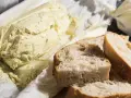 Ein Laib Kräuterbutter, wie Cafe de Paris Butter, liegt neben frisch geschnittenem Baguette.