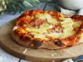 Eine köstliche Pizza Hawaii mit saftigen Ananasstücken und Schinken auf knusprigem Teig, garniert mit Kräutern.