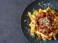 Jamie Oliver Bolognese auf Bandnudeln, garniert mit frischen Kräutern und Parmesan. Ein herzhaftes Gericht, das Lust auf mehr macht.