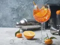 Erfrischender Aperol Spritz mit Orangenscheiben und Eiswürfeln, garniert mit Rosmarin. Ein Hauch von Sommer.