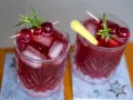 Zwei erfrischende, rote Mocktails mit Kirschen und Rosmarin, perfekt für einen entspannten Abend.