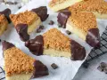 Dreiecke von einem Nussecken Rezept, mit Schokoladenboden und knuspriger Nussdecke, auf Backpapier arrangiert.