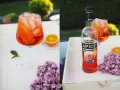 Erfrischender alkoholfreier Aperol mit Eis und Orangenscheiben, daneben eine Flasche Apice Aperitif Bitter.