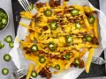 Pommes Frites mit Hackfleisch, Bohnen, Mais und geschmolzenem Käse, garniert mit Jalapeños. Ein köstliches Gericht mit **Chilli Cheese Sauce**.
