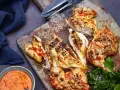 Saftiges Peri Peri Chicken, gegrillt und mit einer würzigen Sauce serviert, liegt auf einem Holzbrett.