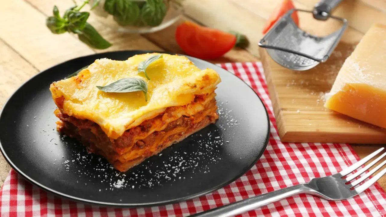 Ein Stück Lasagne mit Käse überbacken, garniert mit Basilikum. Perfekt für ein köstliches Lasagne Rezept.