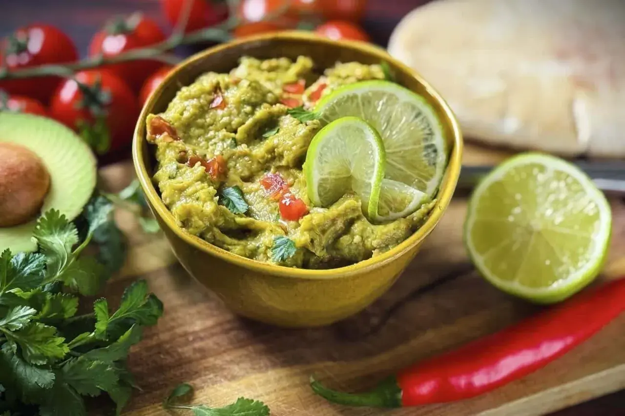 Frisches Guacamole-Rezept mit Limettenscheiben, Koriander, Tomaten und Chili. Perfekt zum Dippen!