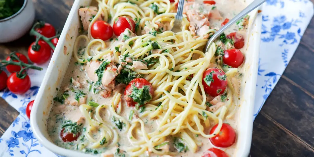 Cremige Lachs Spinat Pasta mit Kirschtomaten in einer Auflaufform, bereit zum Servieren.
