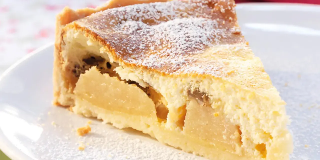 Ein Stück saftiger Apfelkuchen mit Quark, bestäubt mit Puderzucker, auf einem weißen Teller.