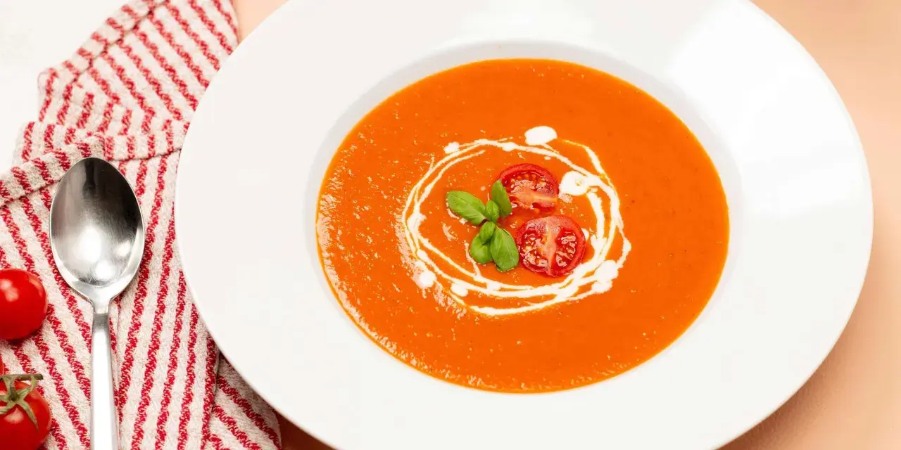 Ein Teller cremiger Tomatensuppe, garniert mit frischen Tomaten und Basilikum. Perfekt für ein einfaches Tomatensuppe Rezept mit frischen Tomaten.