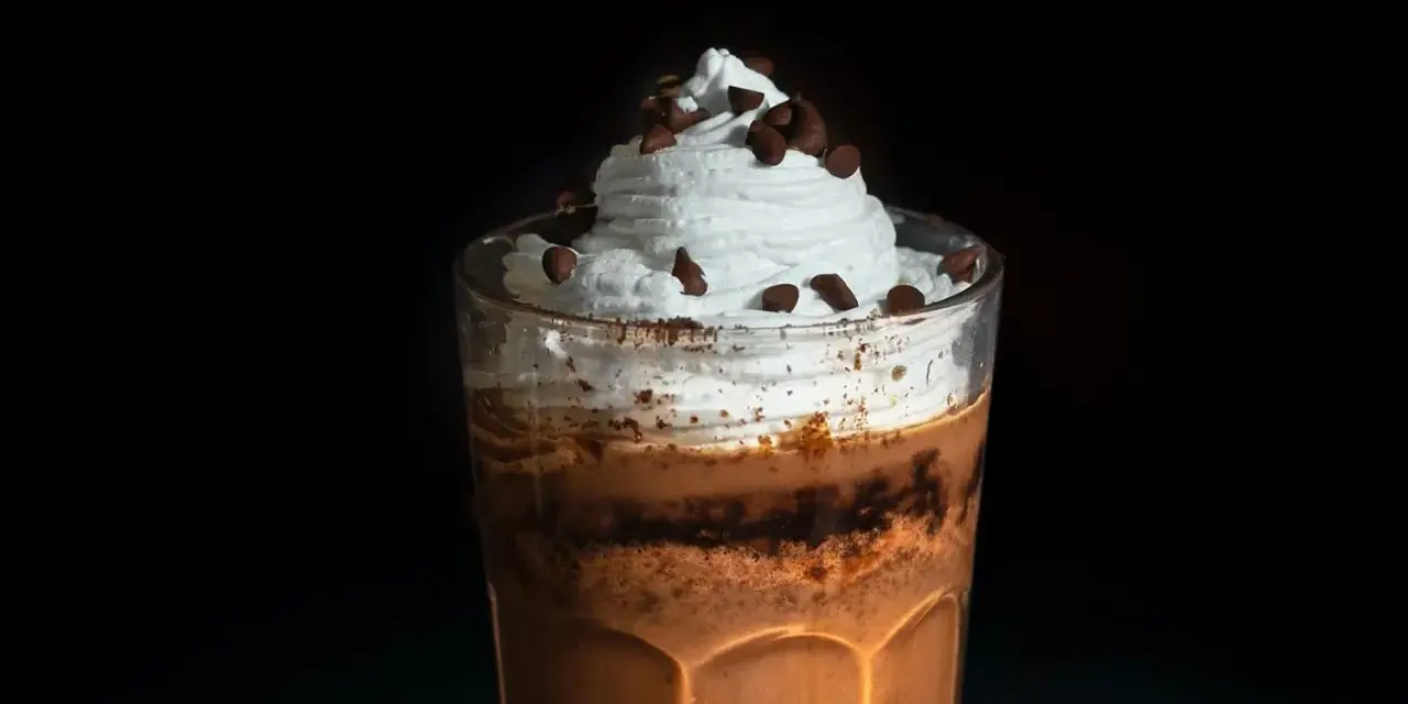 Eiskaffee selbst machen: Ein Glas mit cremigem Eiskaffee, Sahne und Schokostückchen. Perfekt für heiße Tage!