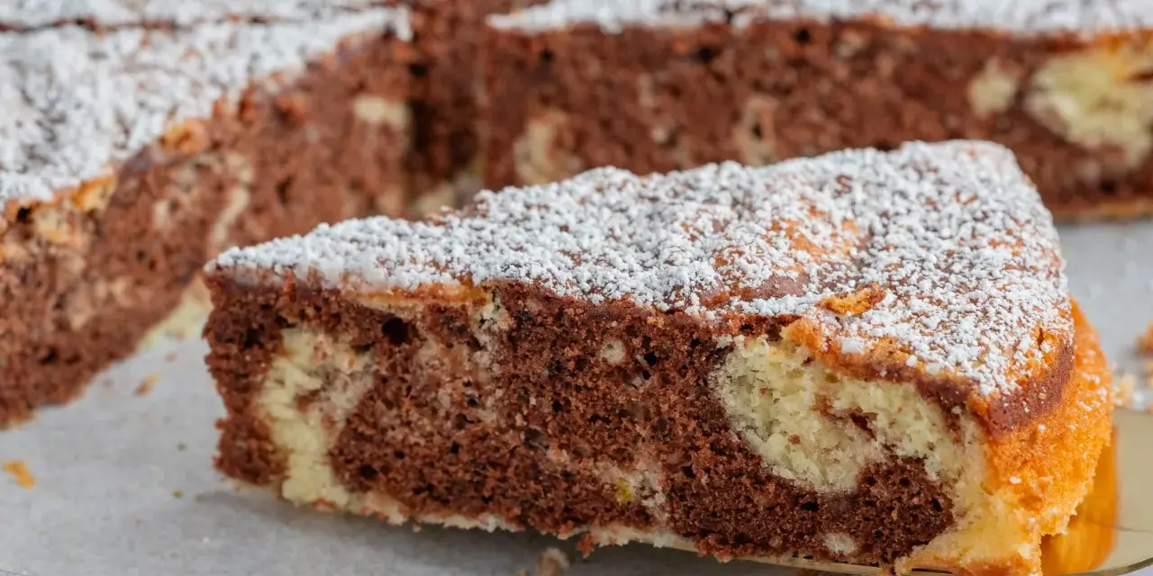 Ein Stück saftiger Marmorkuchen, bestäubt mit Puderzucker. Dieses fluffiger wolkenkuchen rezept ist ein Genuss!