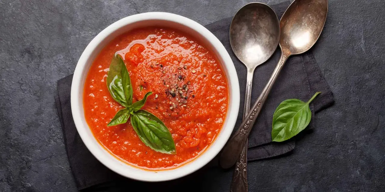 Schüssel mit frischer Tomatensuppe, garniert mit Basilikum. Perfekt, um Tomatensauce selber machen zu lernen.