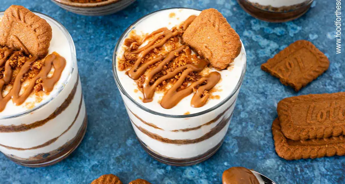 Schichtdessert im Glas: cremiges Lotus Cheesecake mit Keksbröseln und Karamellsoße, garniert mit einem Lotus Keks.