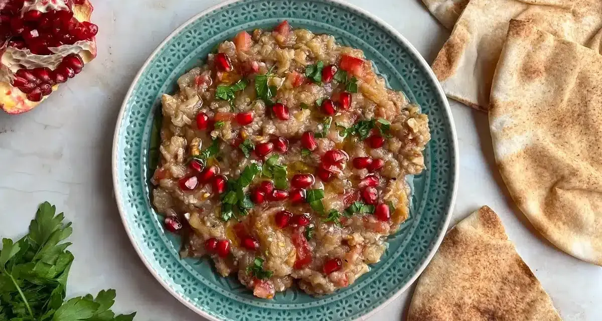 Baba ganoush, ein cremiger Auberginen-Dip, garniert mit Granatapfelkernen und Petersilie, serviert mit Pitabrot.