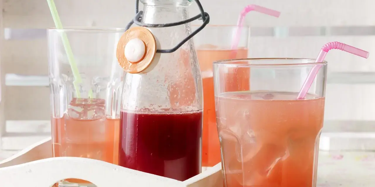 Erfrischender Rhabarbersirup im Glas mit Eis und Strohhalm. Ein tolles Rezept für den Sommer!