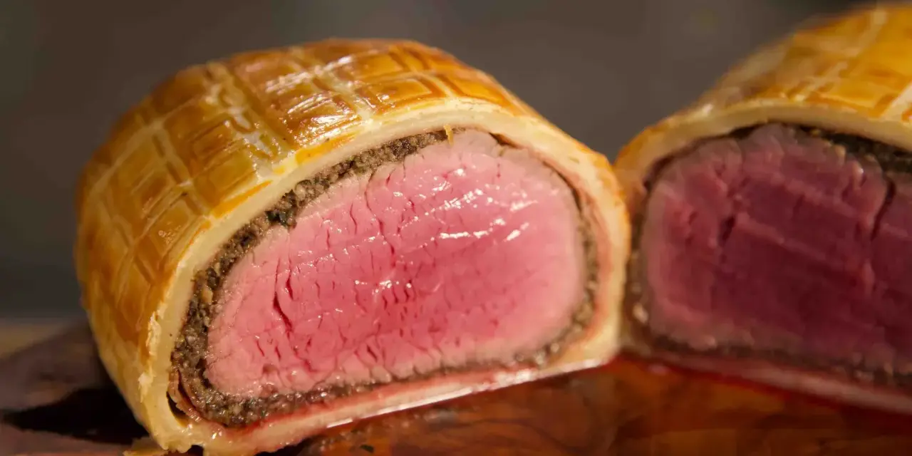 Ein perfekt zubereitetes Beef Wellington, saftig rosa im Inneren, umhüllt von goldbraunem Blätterteig.