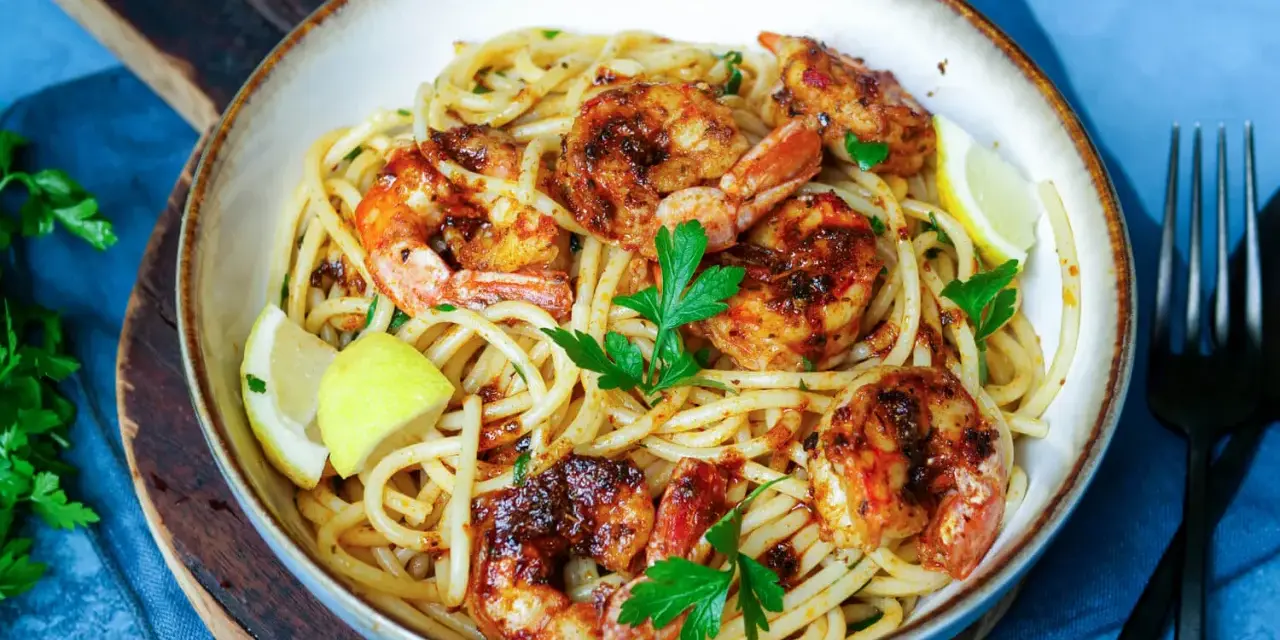 Ein Teller mit köstlichen Spaghetti mit Garnelen, garniert mit frischer Petersilie und Zitronenspalten.