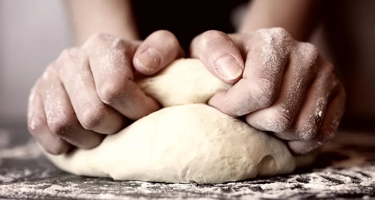 Hände kneten den pizzateig. Wie lange kneten? Bis er geschmeidig ist!