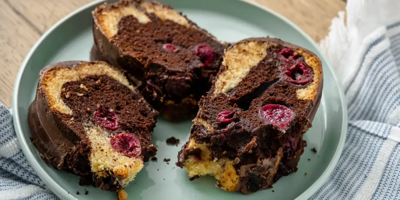 Drei saftige Stücke Marmorkuchen mit Kirschen und Schokoladenglasur auf einem Teller.