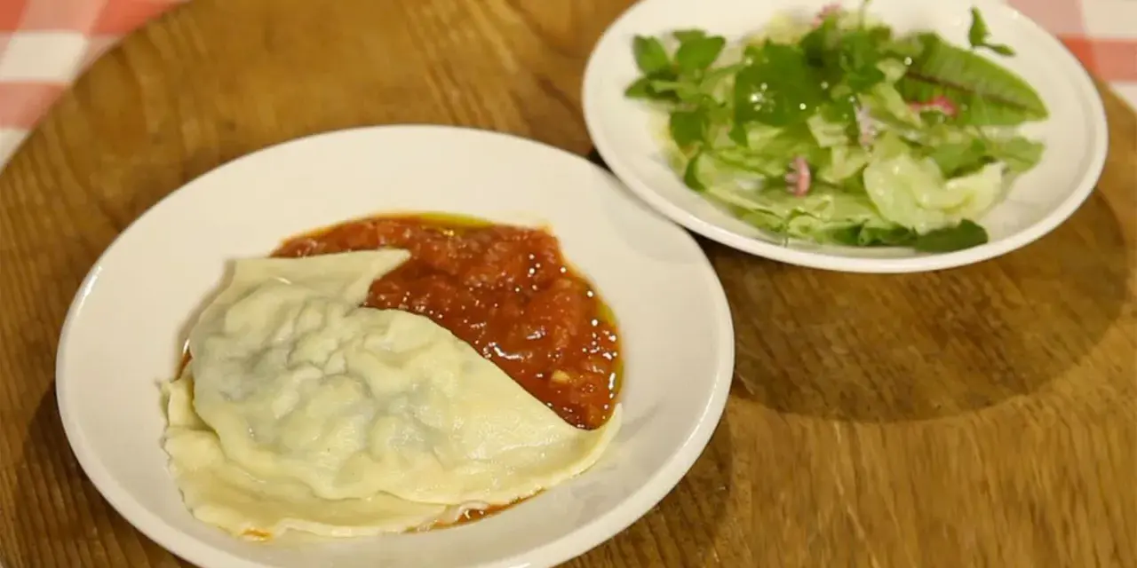 Ein Teller mit Maultaschen in Tomatensoße und ein kleiner Salat. Perfekt für ein schnelles Maultaschen Rezept.