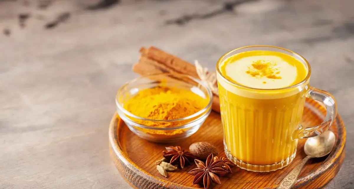 Ein Glas goldene Milch mit Kurkumapulver, Zimtstangen und Sternanis. Perfekt für ein wärmendes goldene milch rezept.