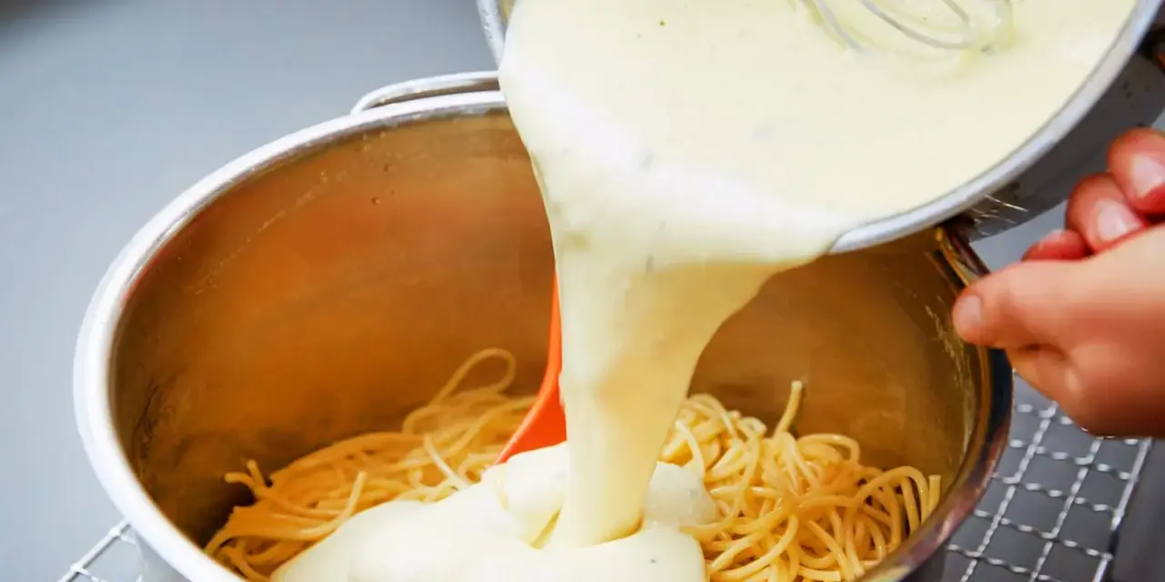 Cremige Käsesauce wird über Spaghetti gegossen. Ein einfaches Käsesauce Rezept für ein köstliches Gericht.
