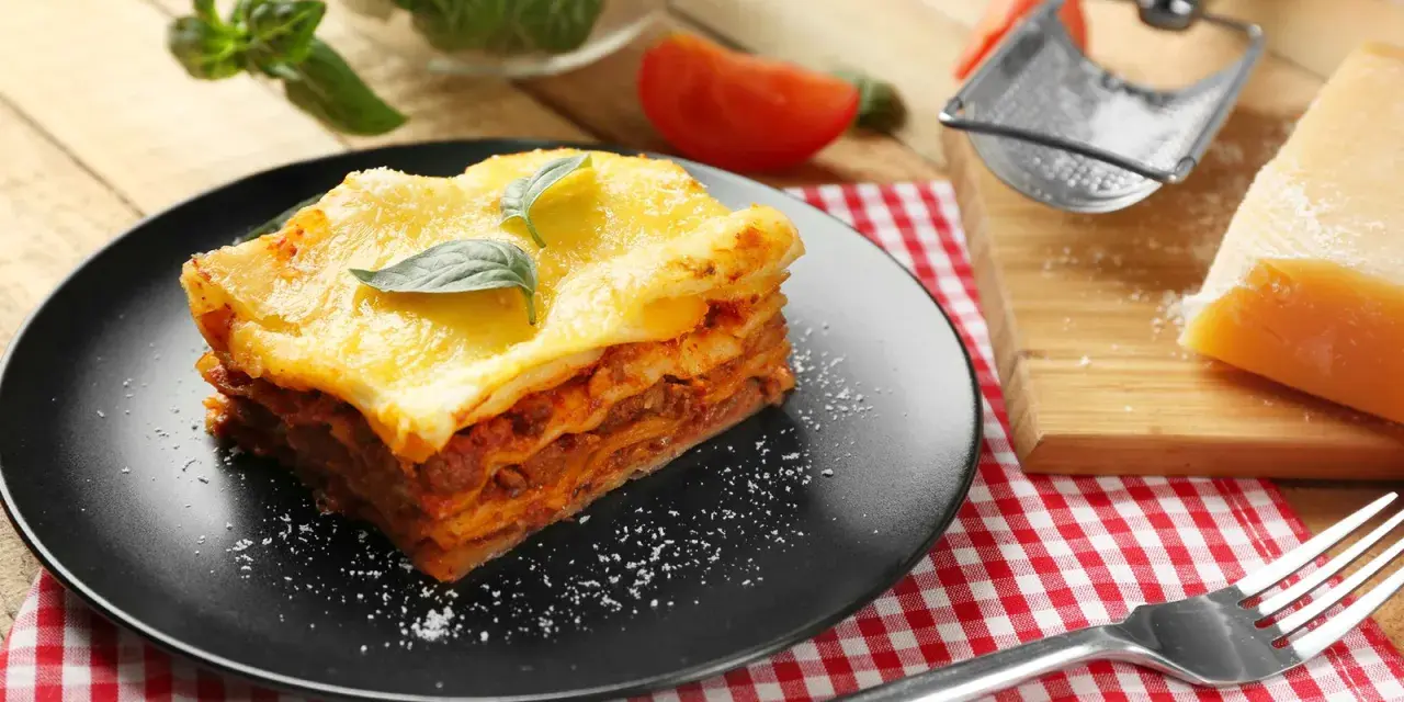 Ein Stück Lasagne mit Käse überbacken, garniert mit Basilikum. Perfekt für ein köstliches Lasagne Rezept.