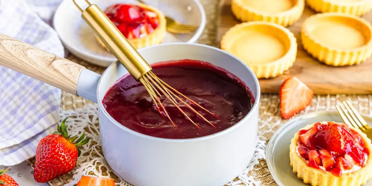 Frisch zubereiteter roter Tortenguss in einem Topf, bereit, um kleine Törtchen zu verfeinern. So einfach ist tortenguss selber machen!