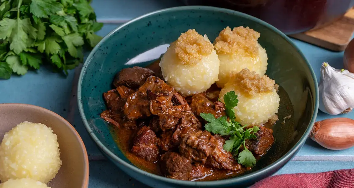 Herzhaftes Rindergulasch nach Omas Rezept, serviert mit Klößen und frischer Petersilie. Ein Klassiker, der immer schmeckt.